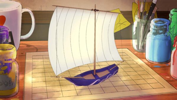 Auf dem Bild ist ein Arbeitsplatz zu sehen, in dessen Mitte ein lilafarbenes Modellboot mit einem großen weißen Segel steht.
