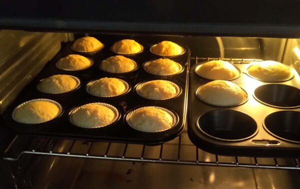 Zu sehen sind zwei Muffinbleche, die im Backofen auf der mittleren Schiene sind. Insgesamt sind 15 Muffins im Blech.