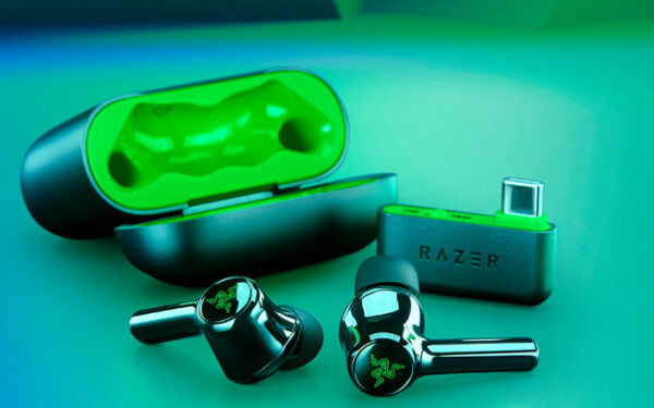 Schwarz-grüne Gaming-Earbuds vor ihrem Ladecase. Auch der USB-C Dongle ist mit abgebildet.