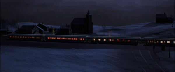 Ein Zug fährt durch eine Schneelandschaft und hält in einem Ort mit einer Kirche und drei Häusern.